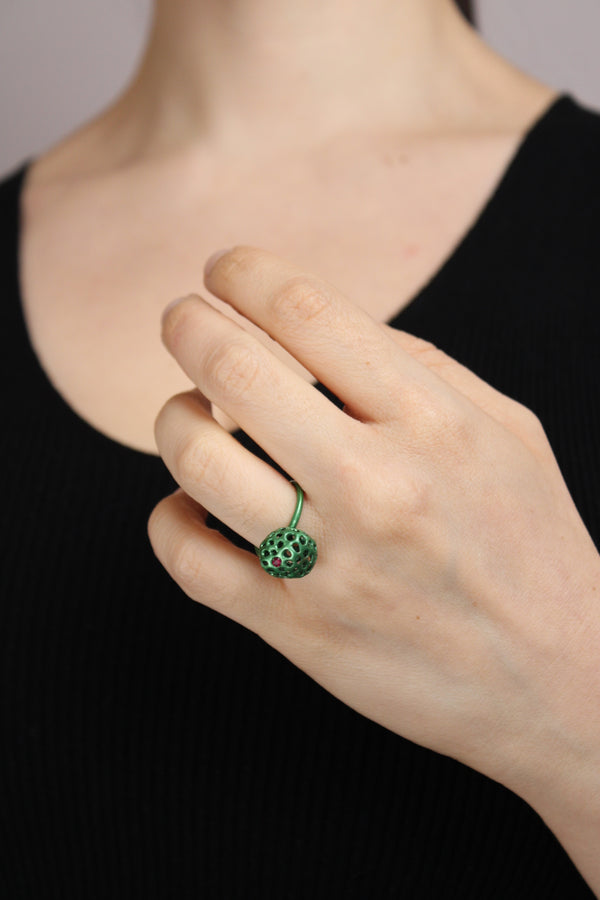 Hand wearing a green ring with a black background