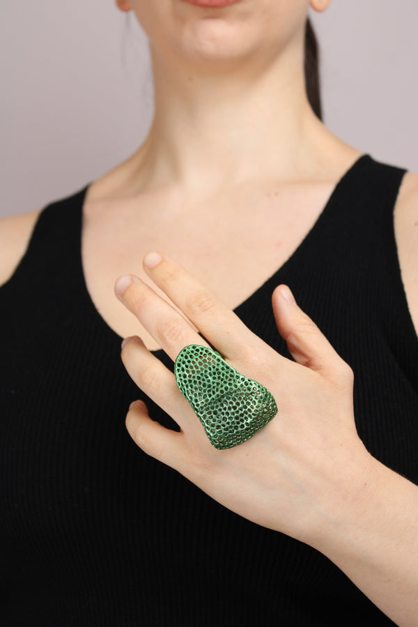 Person wearing a green ring on a blurred background