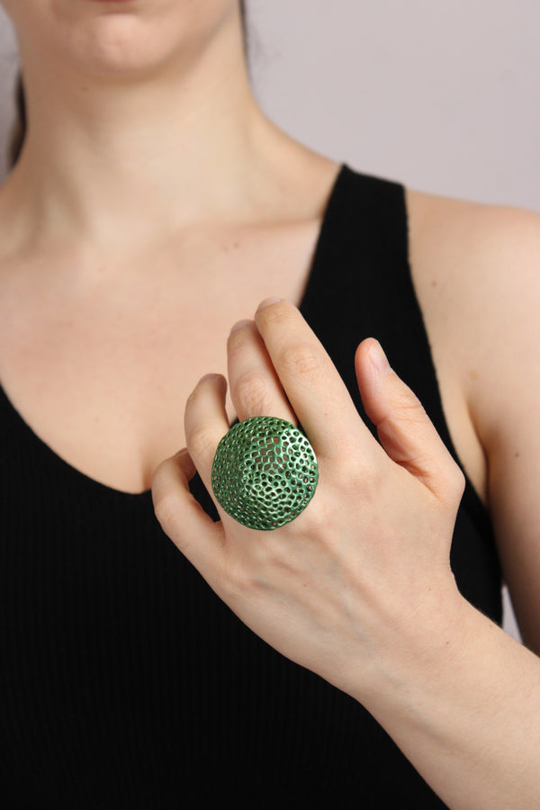 Person wearing a green textured ring on a neutral background