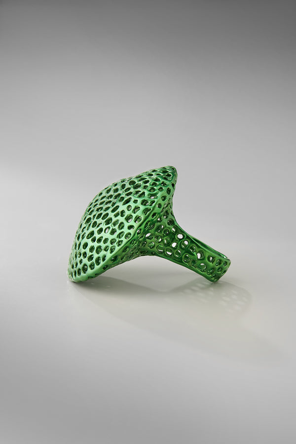 Green sculptural ring on a gray background