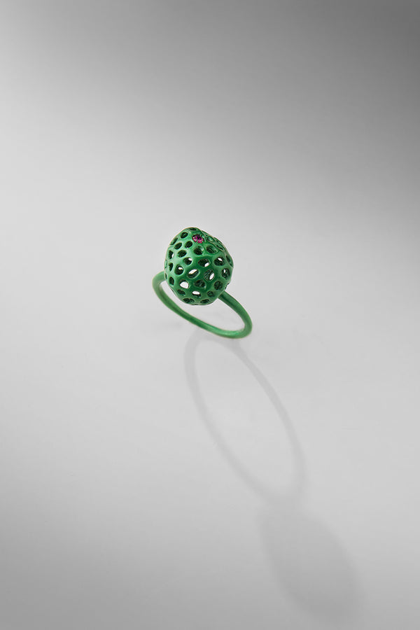 Green ring with one embedded ruby stone on a gray background