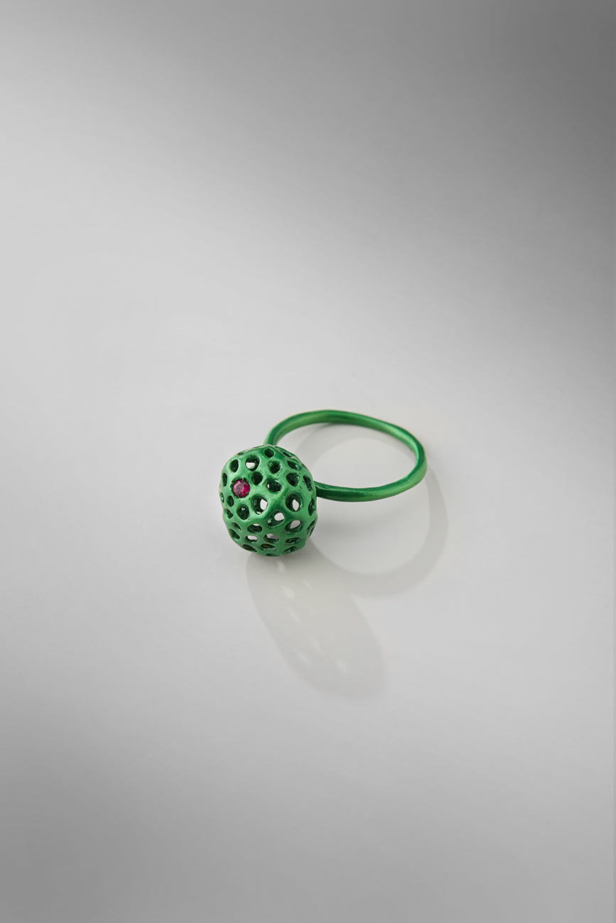 Green ring with a textured ball design on a gray background